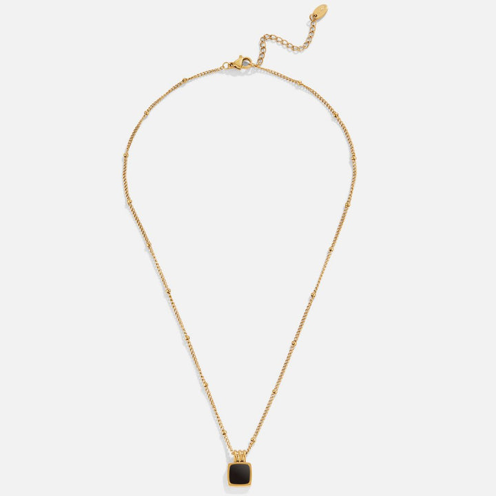 Selina – Collar dorado con piedra oscura.